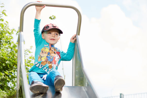 Ein Junge sitzt oben auf einer Rutsche.