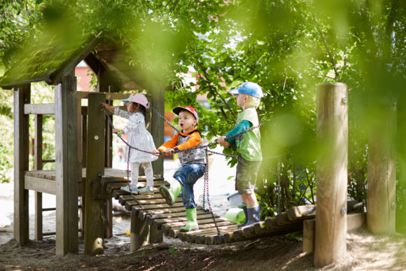 Drei Kinder spielen auf einem Klettergerüst.