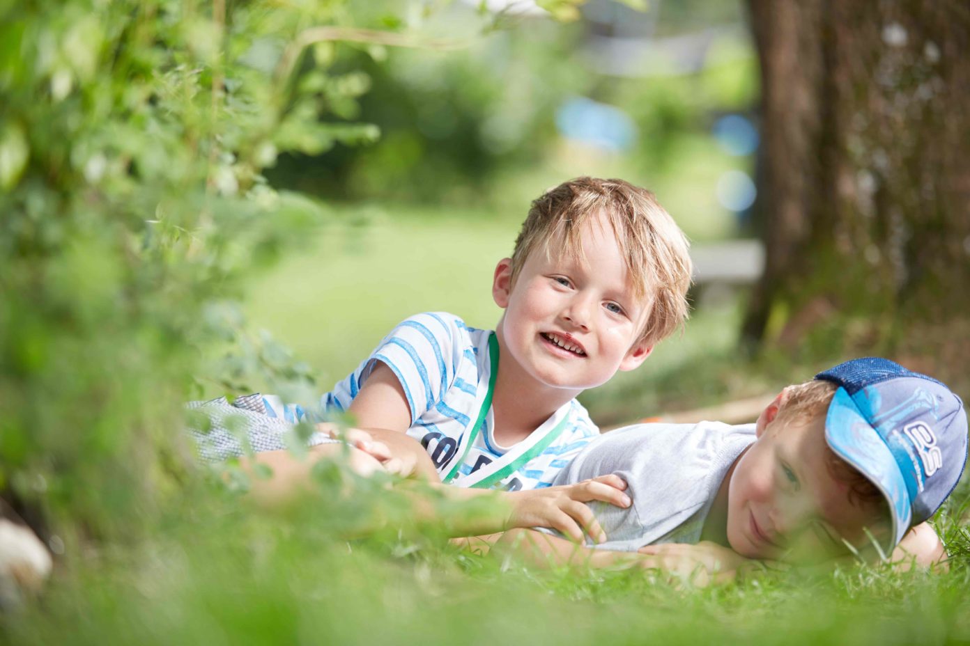 Zwei Jungen liegen auf dem Kita-Gelände im Gras.