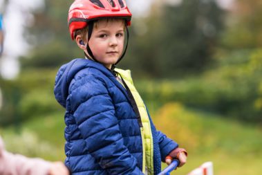 Ein Junge steht auf seinem Roller und guckt in die Kamera.