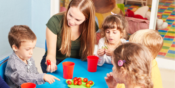 Erzieherin mit Kindern beim Essen