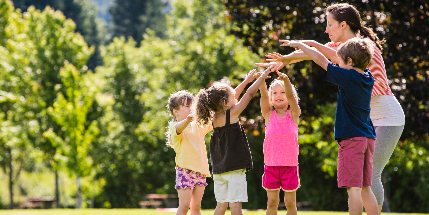 Kinder und Erzieherin spielen im Freien.