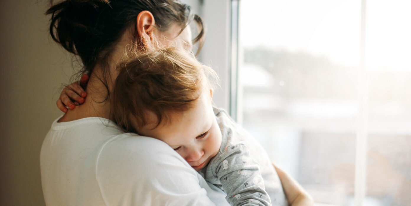 Ein Kind auf dem Arm einer Frau kuschelt sich an sie.
