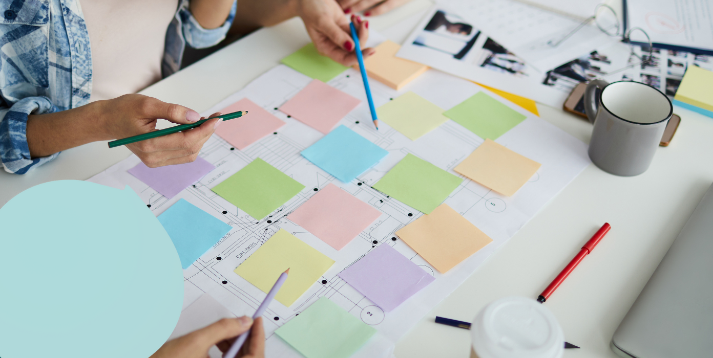 Planung von Räumen mithilfe eines Grundrisses, auf dem verschiedenfarbige Zettel verteilt sind.