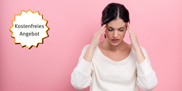 Eine junge gestresste Frau, greift sich an die Schläfen.