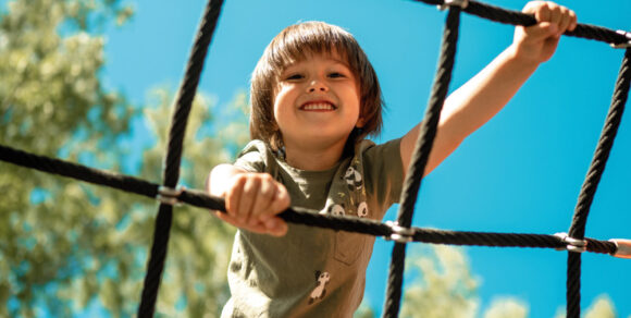 Ein Kind klettert an einem Kletternetz.