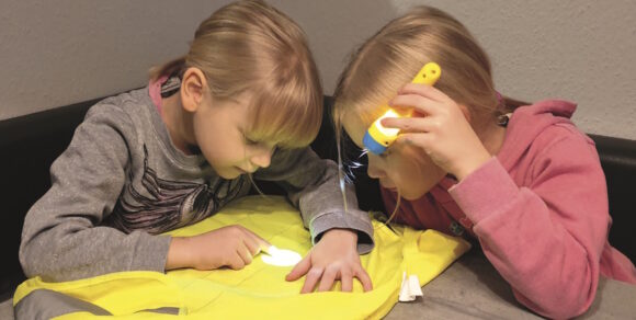 Zwei Kinder erforschen ein Stück Stoff mit einer Taschenlampe