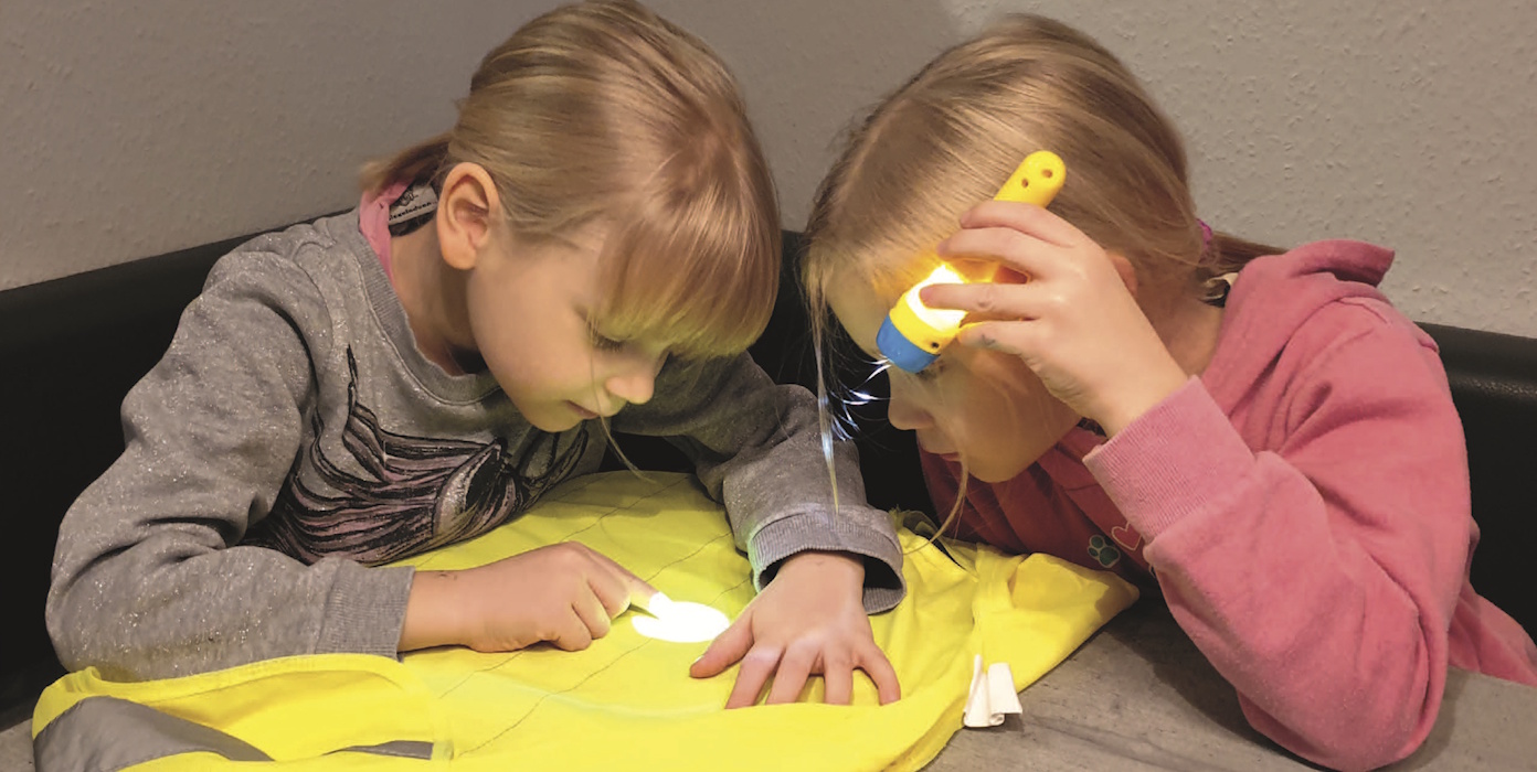 Zwei Kinder erforschen ein Stück Stoff mit einer Taschenlampe
